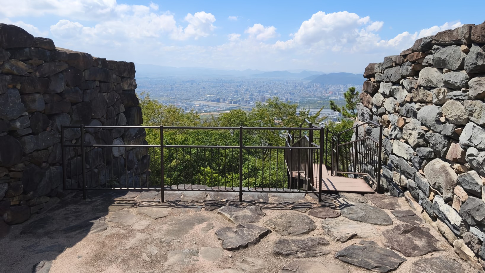 Ancient stone walls, the ruins of a fortress gate, frame a panoramic view of Takamatsu City.