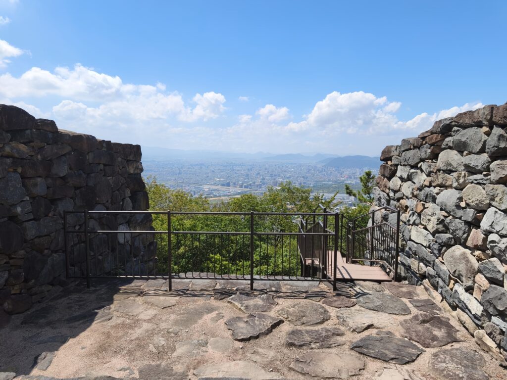 Ancient stone walls, the ruins of a fortress gate, frame a panoramic view of Takamatsu City.