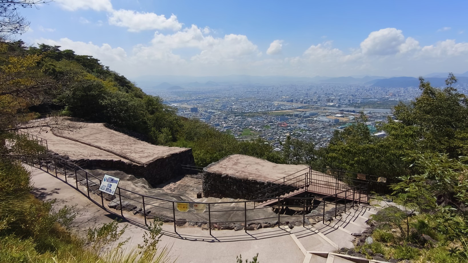 The preserved ruins of an ancient fortress in the foreground look out over the buildings and fields of Takamatsu City.