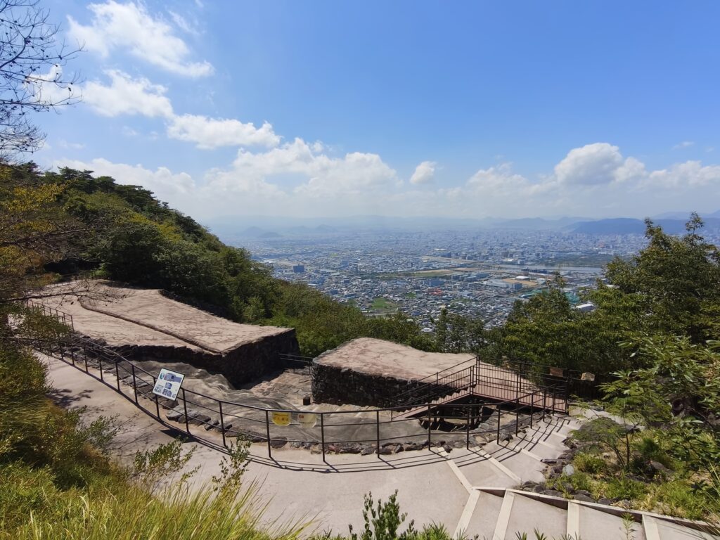 The preserved ruins of an ancient fortress in the foreground look out over the buildings and fields of Takamatsu City.
