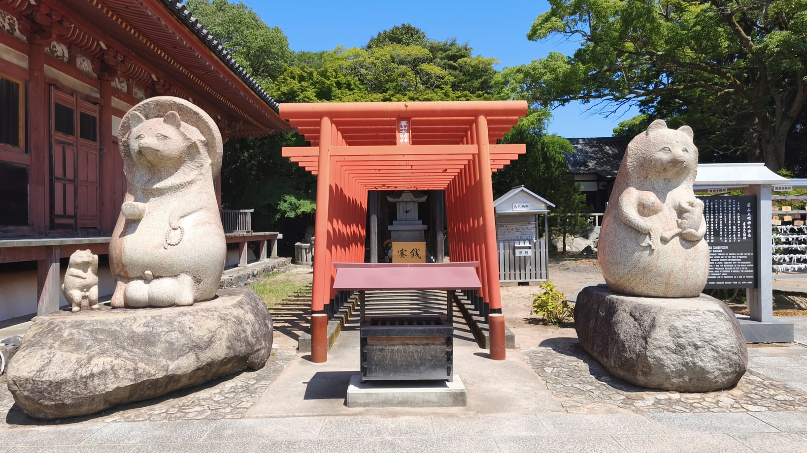 A family of Tanuki guard a series of red torii gates leading to a small Shintō Shrine in the grounds of Yashima-ji Temple