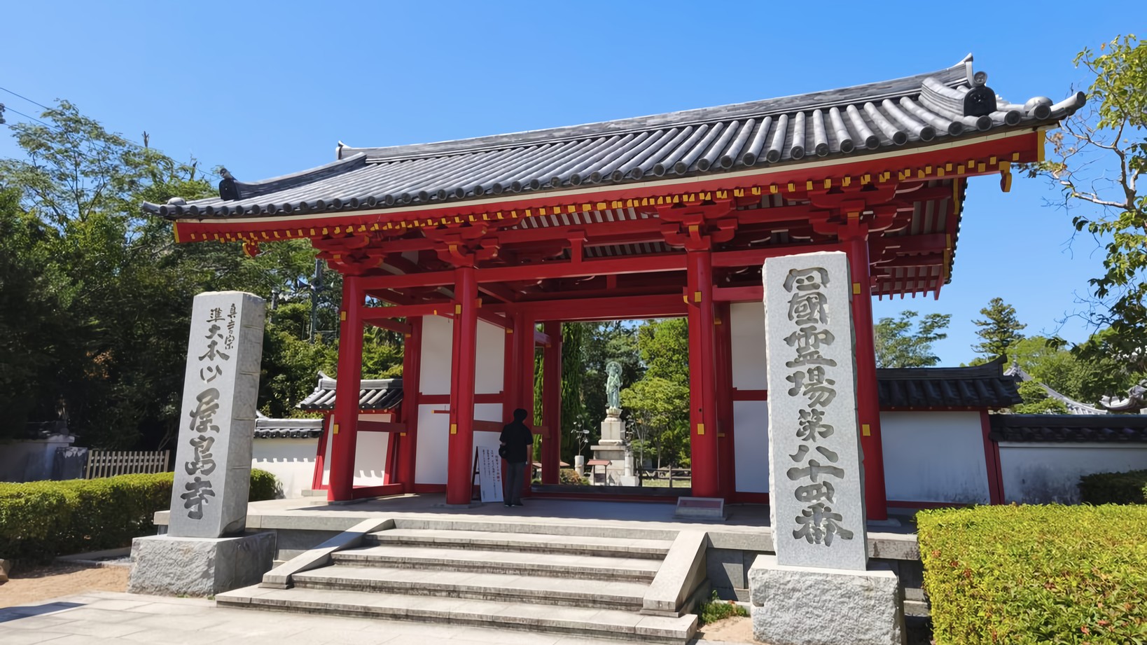 The vermillion gate of Yashima-ji Temple, with stone markers reading "Yashima-ji" and "Shikoku Pilgrimage Temple Number 84" in Chinese characters