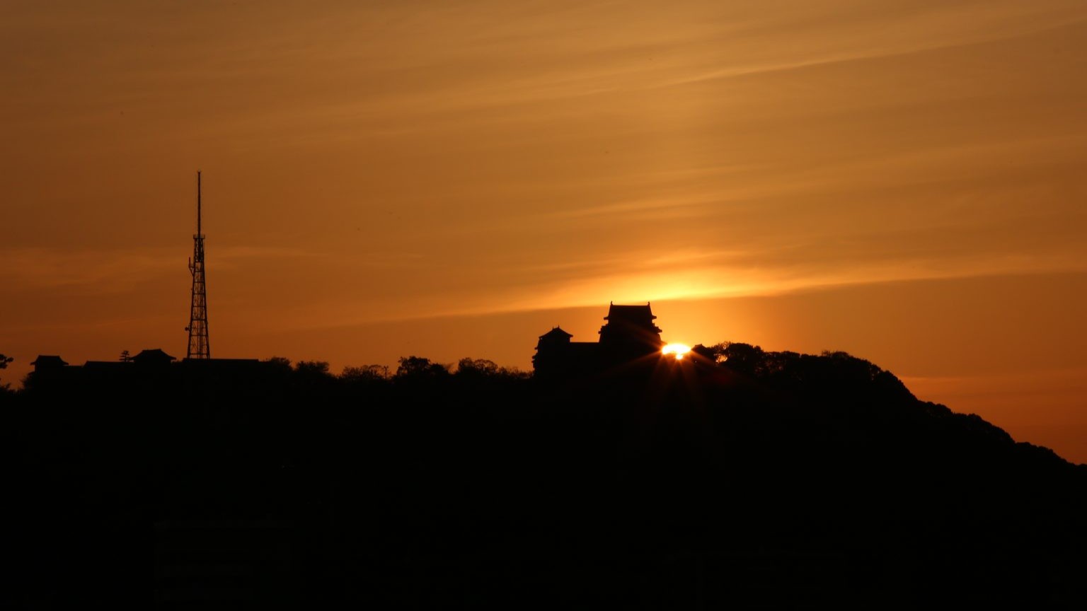 The sun sets behind the Tenshū, the main keep of Matsuyama castle.