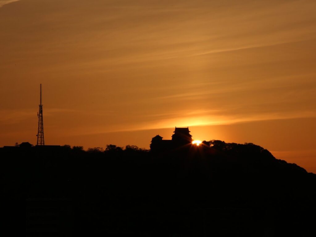 The sun sets behind the Tenshū, the main keep of Matsuyama castle.