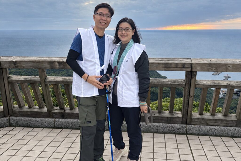Two pilgrims in white hakui vests with a walking staff at an ocean viewpoint on the Shikoku 88 Temple Pilgrimage